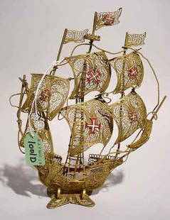 PORTUGUESE FILIGREE BRASS MODEL OF A THREE-MASTE: PORTUGUESE FILIGREE BRASS MODEL OF A THREE-MASTED SHIP, having enamel Maltese Cross decorated medallions; 8-3/4 inch height; 6-3/4 inch length (Est. 25-45)