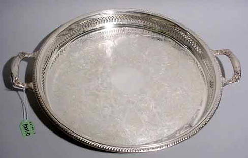 SILVERPLATED CIRCULAR FOOTED GALLERY TRAY, havin: SILVERPLATED CIRCULAR FOOTED GALLERY TRAY, having floral chased handles and gadrooned edges, the center with foliate and scroll engraving; 15-1/4 inch diameter (Est. 50-75)