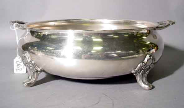 SILVERPLATED CIRCULAR FOOTED CASSEROLE, by Poole,: SILVERPLATED CIRCULAR FOOTED CASSEROLE, by Poole, having two foliate scroll handles and four feet, with a Pyrex liner; 13-1/4 inch width; 4-1/4 inch height (Est. 25-35)