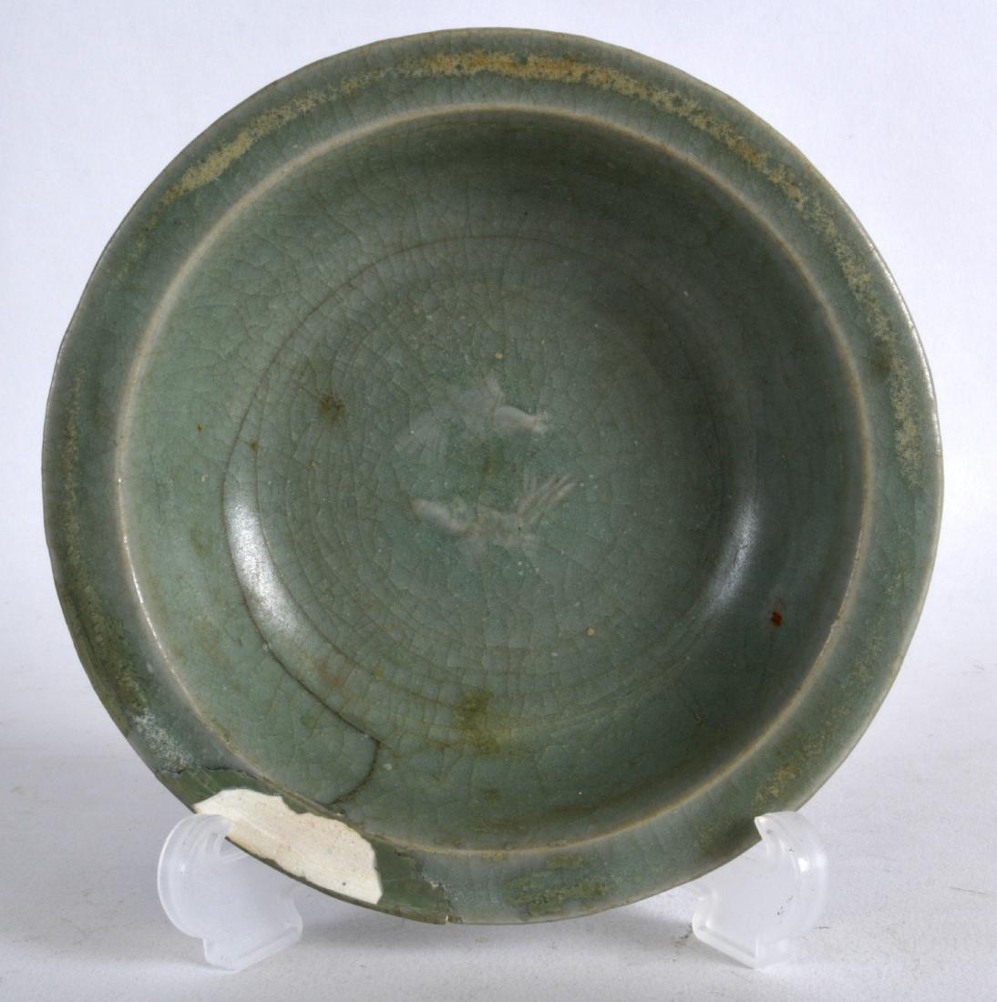 A CHINESE YUAN/MING DYNASTY CELADON DISH decorated in: A CHINESE YUAN/MING DYNASTY CELADON DISH decorated in relief with two stylised fish. 4.75ins diameter.
