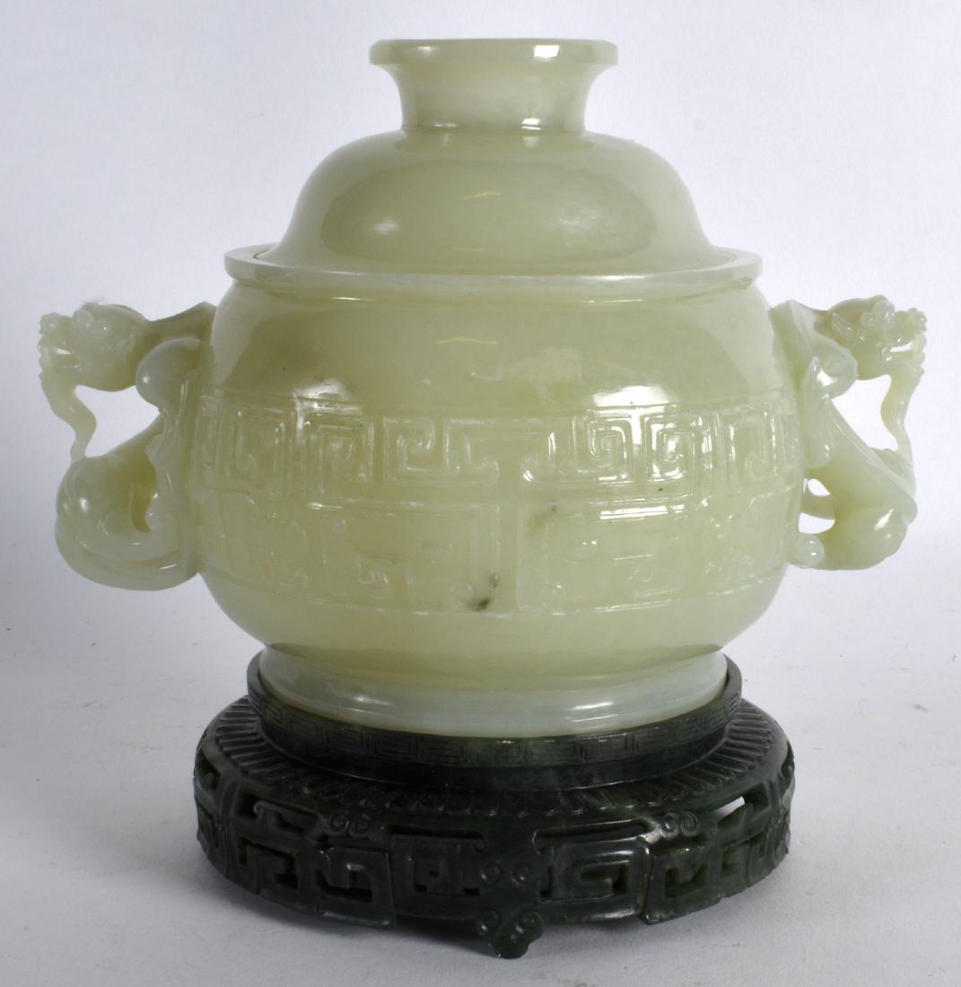 A CHINESE CARVED GREEN JADE TWIN HANDLED CENSER AND: A CHINESE CARVED GREEN JADE TWIN HANDLED CENSER AND COVER upon a spinach jade base, decorated with angular motifs. 6.25ins wide.