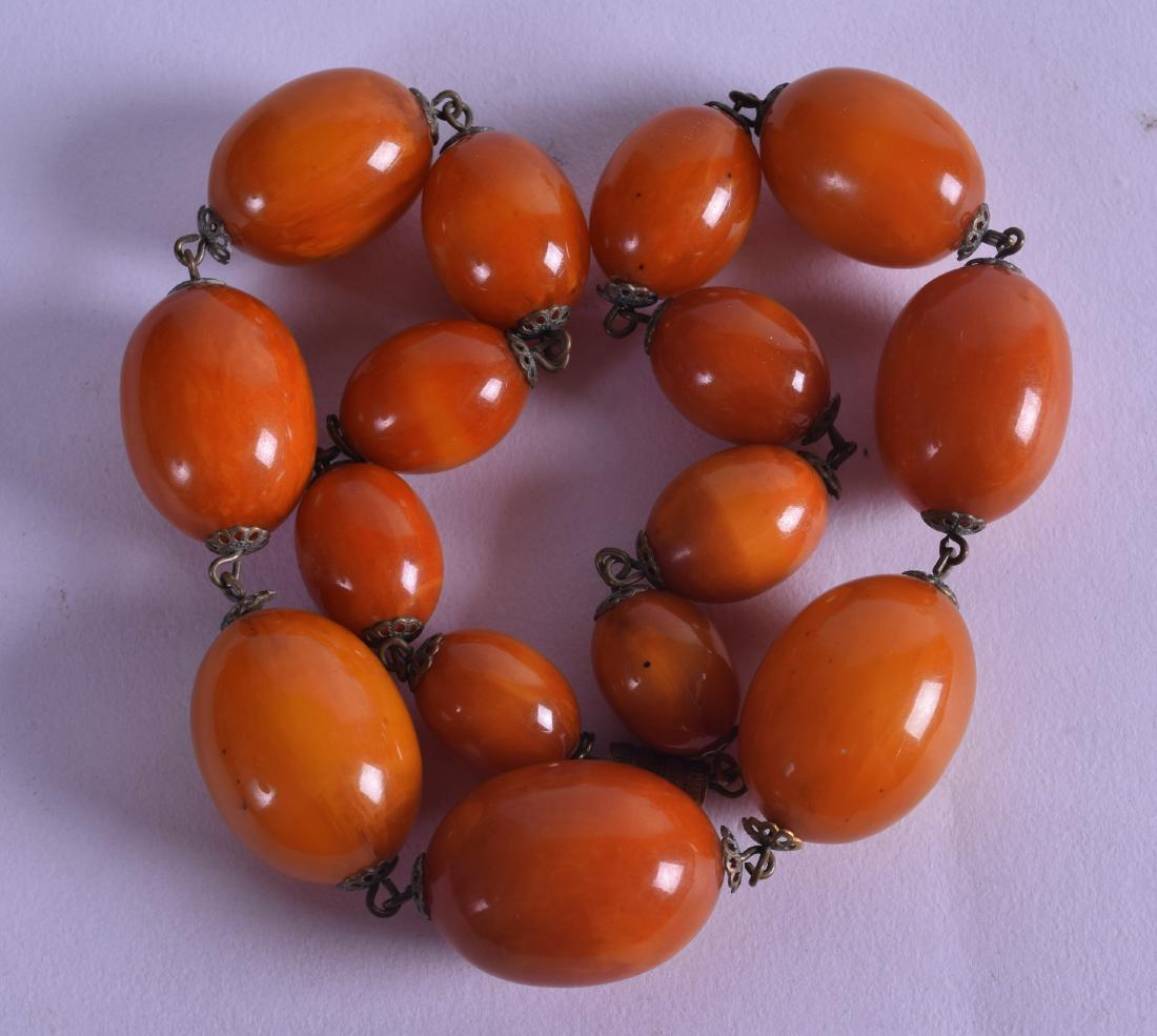 AN EARLY 20TH CENTURY CARVED HONEY AMBER NECKLACE of (1 of 2)