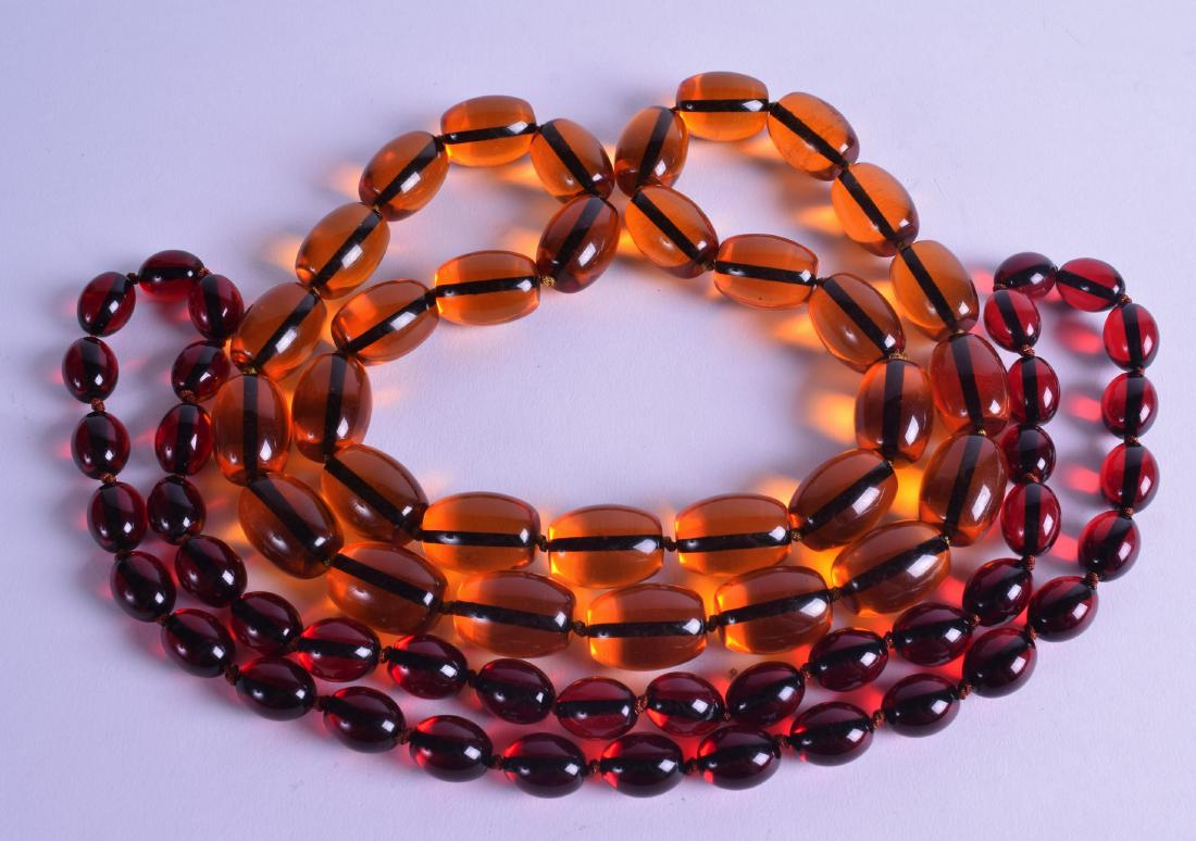 TWO CHINESE CARVED AMBER TYPE NECKLACES. 82 cm & 74 cm (1 of 2)