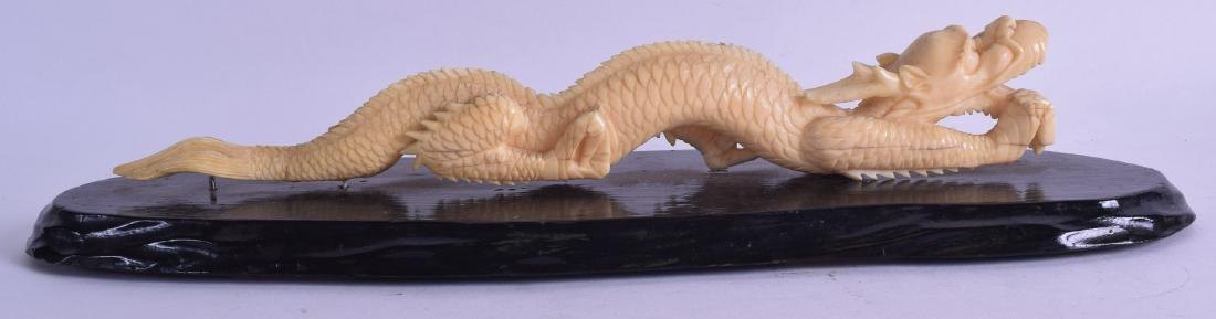 A 19TH CENTRY JAPANESE MEIJI PERIOD CARVED BONE OKIMONO: A 19TH CENTRY JAPANESE MEIJI PERIOD CARVED BONE OKIMONO modelled as a roaming dragon, upon an ebonised hardwood base. Dragon 29 cm long.