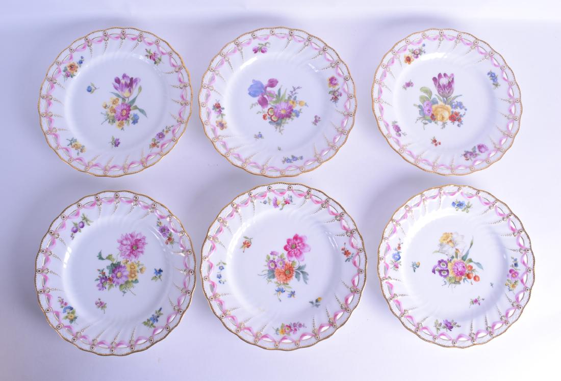 A GOOD SET OF TWELVE ROYAL COPENHAGEN PORCELAIN PLATES: A GOOD SET OF TWELVE ROYAL COPENHAGEN PORCELAIN PLATES painted with various floral sprays within a reticulated gilt border. 23 cm diameter. (12)