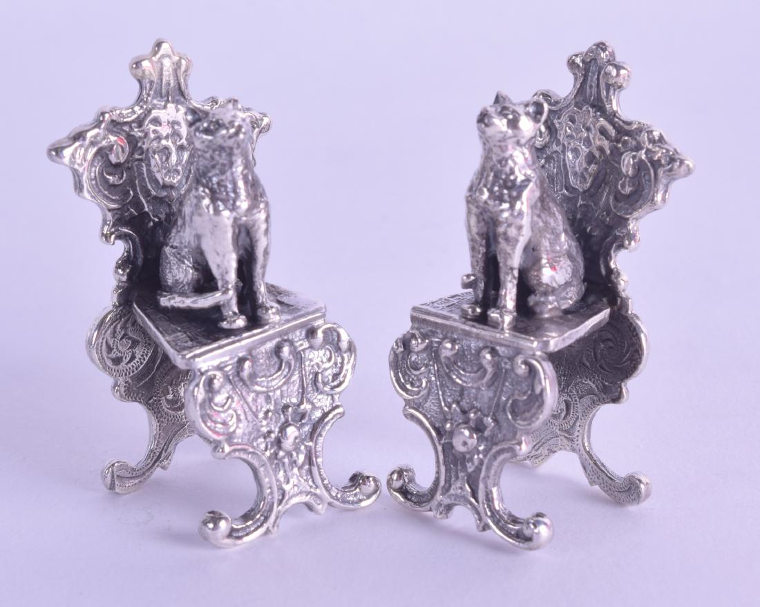 A PAIR OF NOVELTY SILVER CHAIRS surmounted with cats.: A PAIR OF NOVELTY SILVER CHAIRS surmounted with cats.