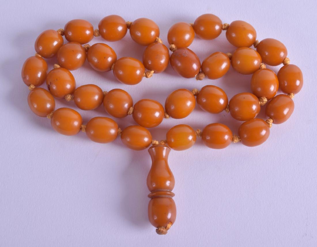 A GOOD EARLY 20TH CENTURY CHINESE TIBETAN CARVED AMBER (1 of 2)