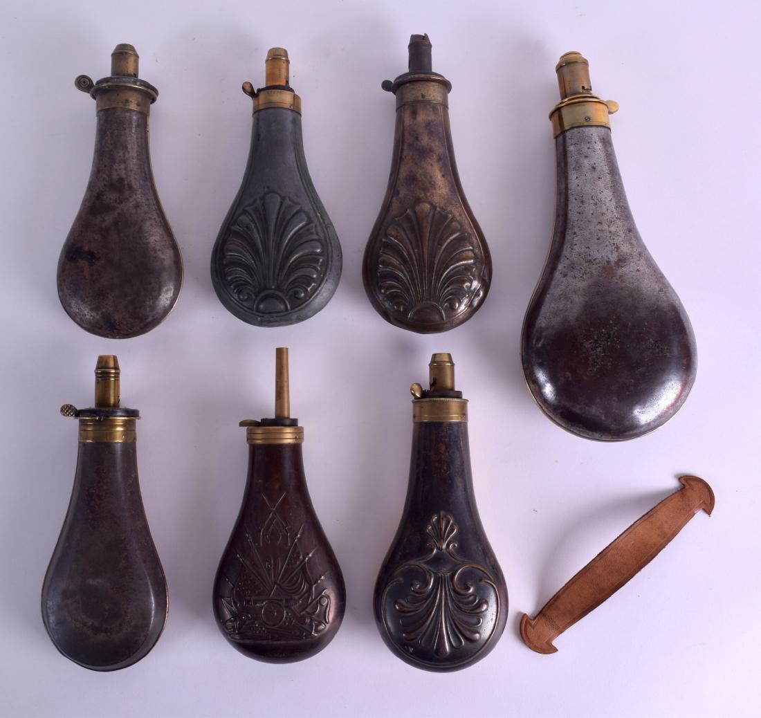 A GROUP OF SEVEN 19TH CENTURY MILITARY POWDER FLASKS in: A GROUP OF SEVEN 19TH CENTURY MILITARY POWDER FLASKS in various forms and designs. Largest 25 cm x 10 cm. (7)