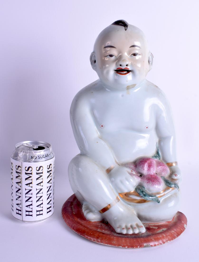 A LARGE LATE 19TH CENTURY CHINESE PORCELAIN FIGURE OF A: A LARGE LATE 19TH CENTURY CHINESE PORCELAIN FIGURE OF A BOY Guangxu, modelled holding peaches upon a coral ground base. 32 cm x 17 cm.
