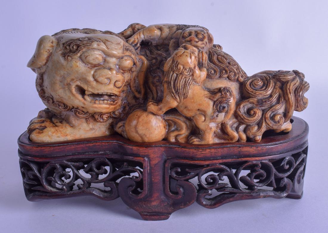 AN 18TH/19TH CENTURY CHINESE CARVED SOAPSTONE FIGURE OF: AN 18TH/19TH CENTURY CHINESE CARVED SOAPSTONE FIGURE OF A BUDDHISTIC LION Qianlong/Jiaqing, modelled with two young upon its back. Figure 20 cm x 11 cm.
