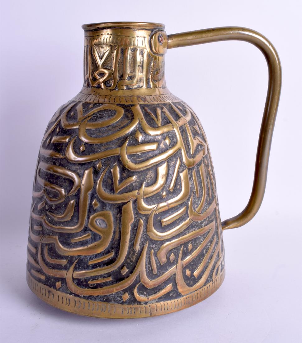 A 19TH CENTURY ARABIC MIDDLE EASTERN BRASS JUG: A 19TH CENTURY ARABIC MIDDLE EASTERN BRASS JUG decorated with Kufic script. 24 cm high.