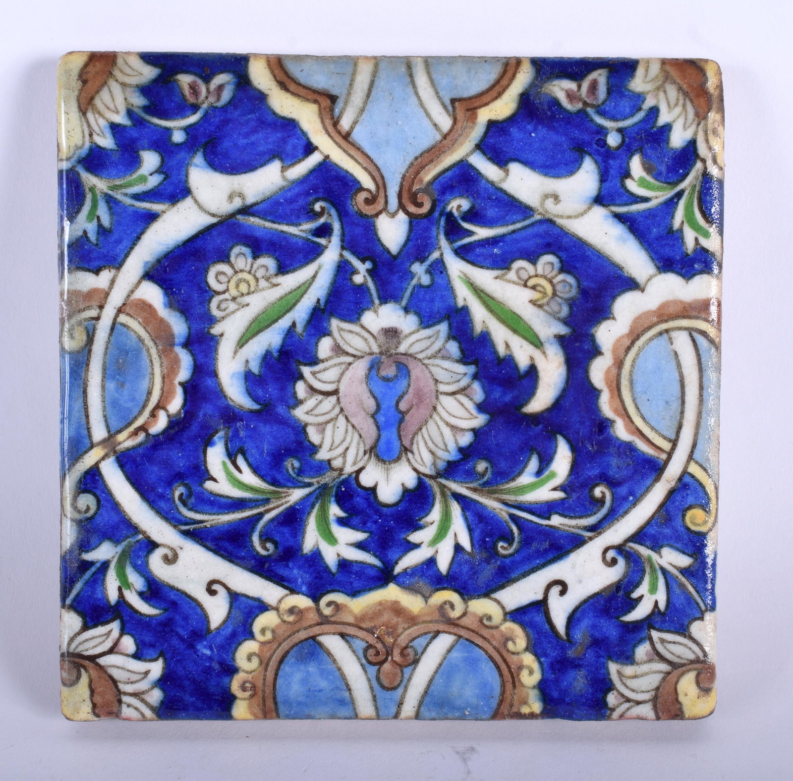 A 19TH CENTURY MIDDLE EASTERN PALESTINE IZNIK SQUARE: A 19TH CENTURY MIDDLE EASTERN PALESTINE IZNIK SQUARE TILE painted with flowers. 16.5 cm square.