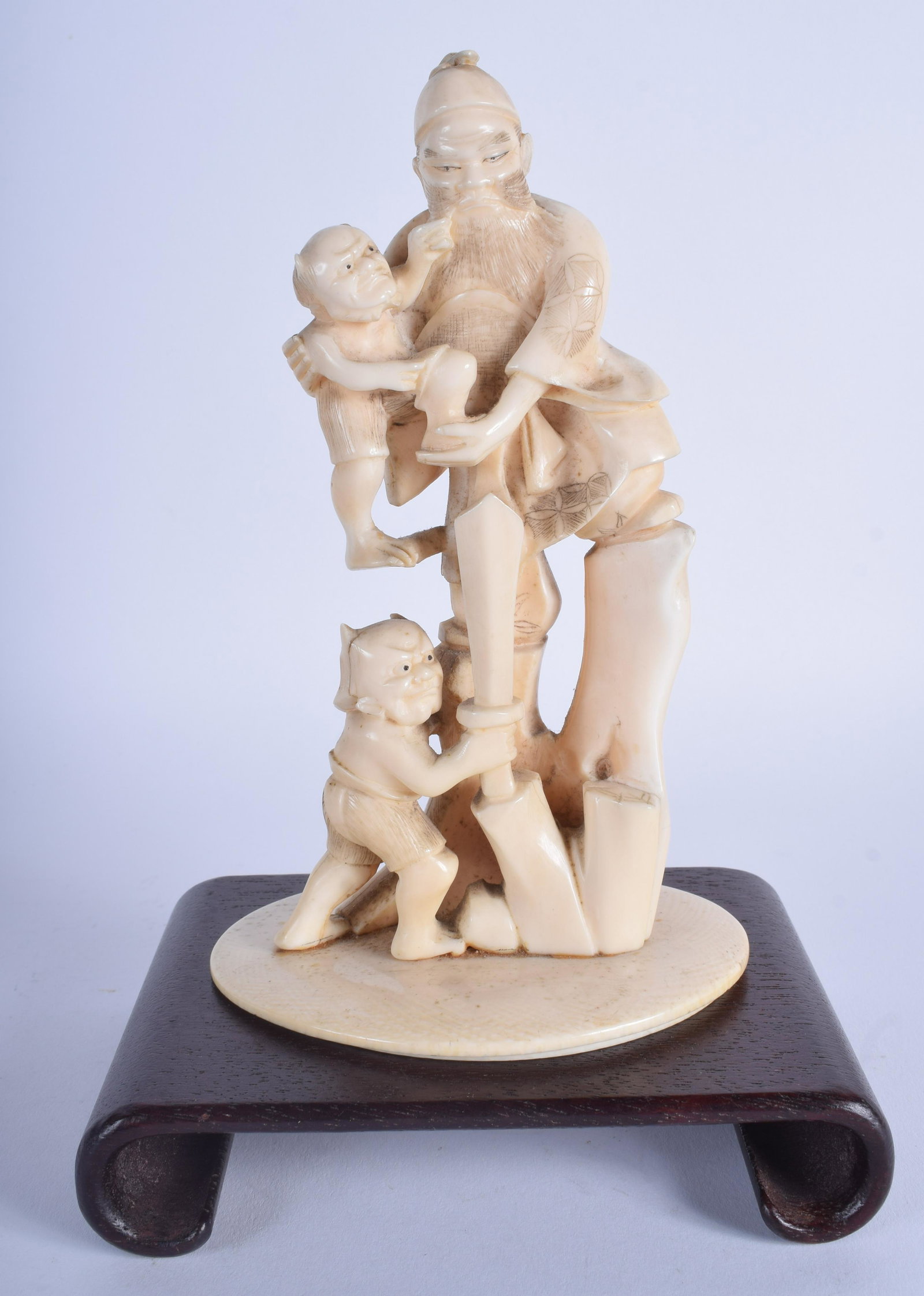 A 19TH CENTURY JAPANESE MEIJI PERIOD CARVED OKIMONO: A 19TH CENTURY JAPANESE MEIJI PERIOD CARVED OKIMONO modelled as a warrior beside two oni. Figure 19 cm x 10 cm.