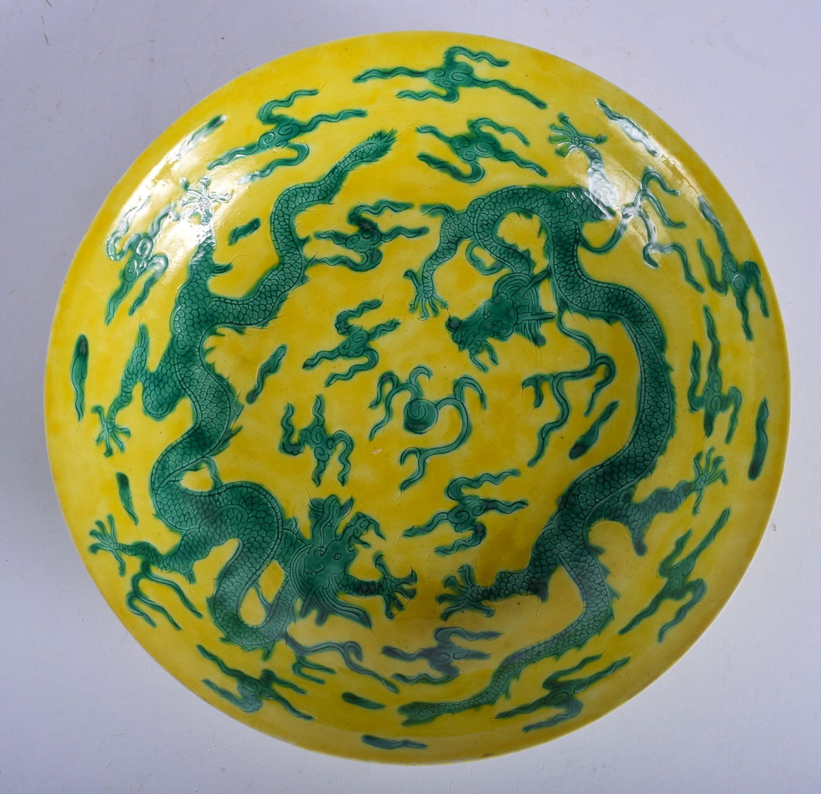 A CHINESE QING DYNASTY YELLOW AND GREEN GLAZED CIRCULAR: A CHINESE QING DYNASTY YELLOW AND GREEN GLAZED CIRCULAR DISH bearing Chenghua marks to base, carved with dragons. 23.5 cm diameter.