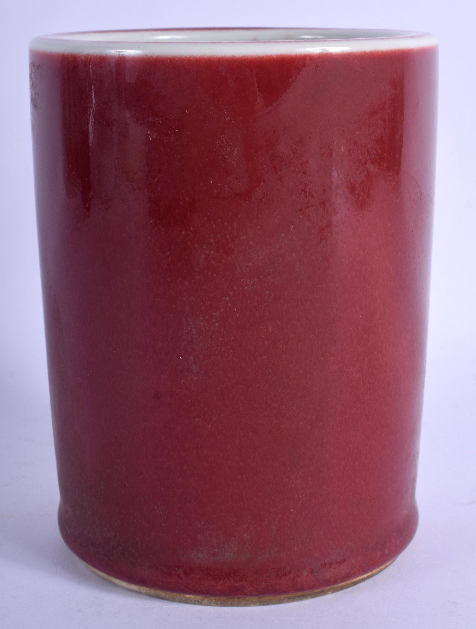 A CHINESE OX BLOOD GLAZED PORCELAIN BRUSH POT BEARING: A CHINESE OX BLOOD GLAZED PORCELAIN BRUSH POT BEARING KANGXI MARKS. 14 cm high.