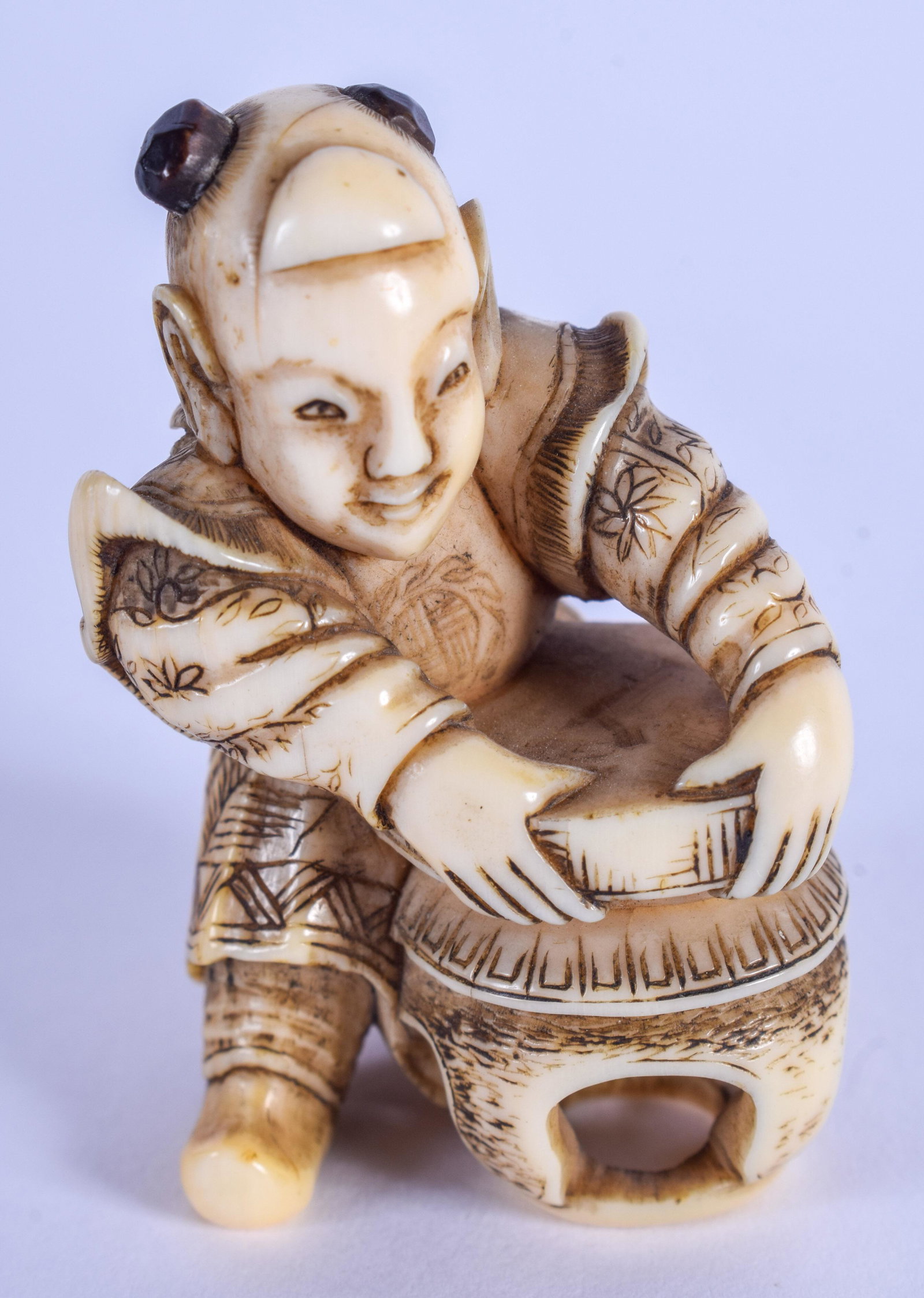 A 19TH CENTURY JAPANESE MEIJI PERIOD CARVED BONE: A 19TH CENTURY JAPANESE MEIJI PERIOD CARVED BONE NETSUKE depicting a boy grasping a table. 4.5 cm x 2.5 cm.