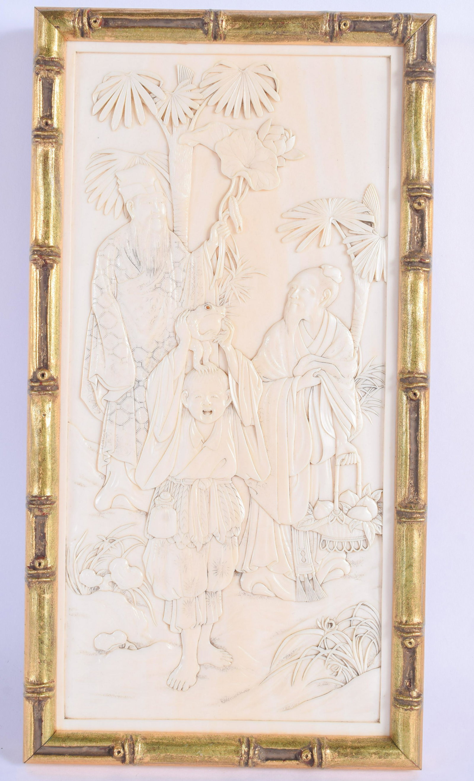 A 19TH CENTURY JAPANESE MEIJI PERIOD CARVED BONE PANEL: A 19TH CENTURY JAPANESE MEIJI PERIOD CARVED BONE PANEL depicting a boy holding aloft a toad beside two scholars. BONE 12 cm x 24 cm.
