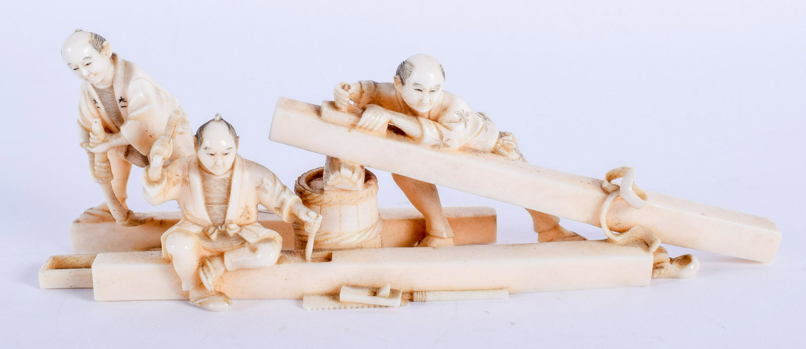 A 19TH CENTURY JAPANESE MEIJI PERIOD CARVED BONE: A 19TH CENTURY JAPANESE MEIJI PERIOD CARVED BONE OKIMONO modelled as three carpenters. 14 cm x 3 cm.