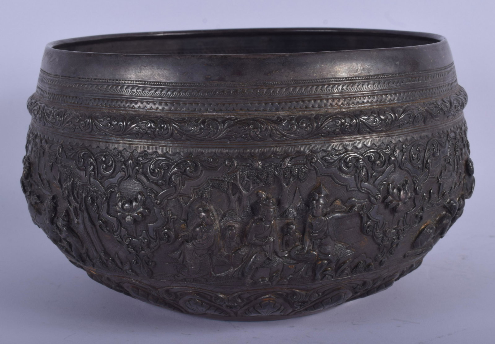 A 19TH CENTURY INDIAN BUDDHISTIC SILVER BOWL AND COVER: A 19TH CENTURY INDIAN BUDDHISTIC SILVER BOWL AND COVER decorated with figures in various pursuits. 800 grams. 21 cm x 14 cm.
