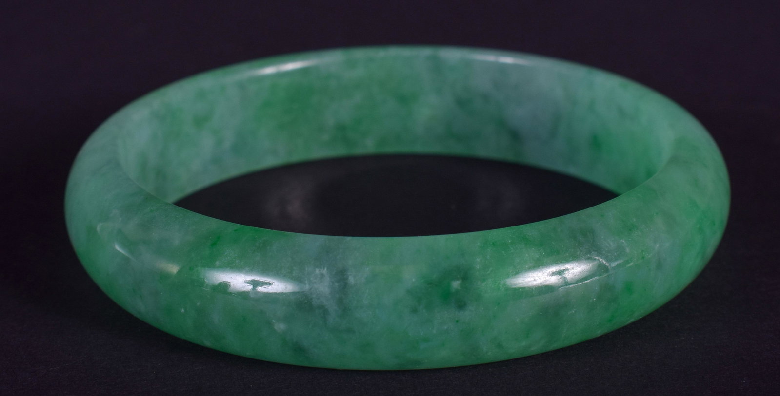 AN EARLY 20TH CENTURY CHINESE CARVED JADEITE BANGLE: AN EARLY 20TH CENTURY CHINESE CARVED JADEITE BANGLE Late Qing. 6.5 cm wide.