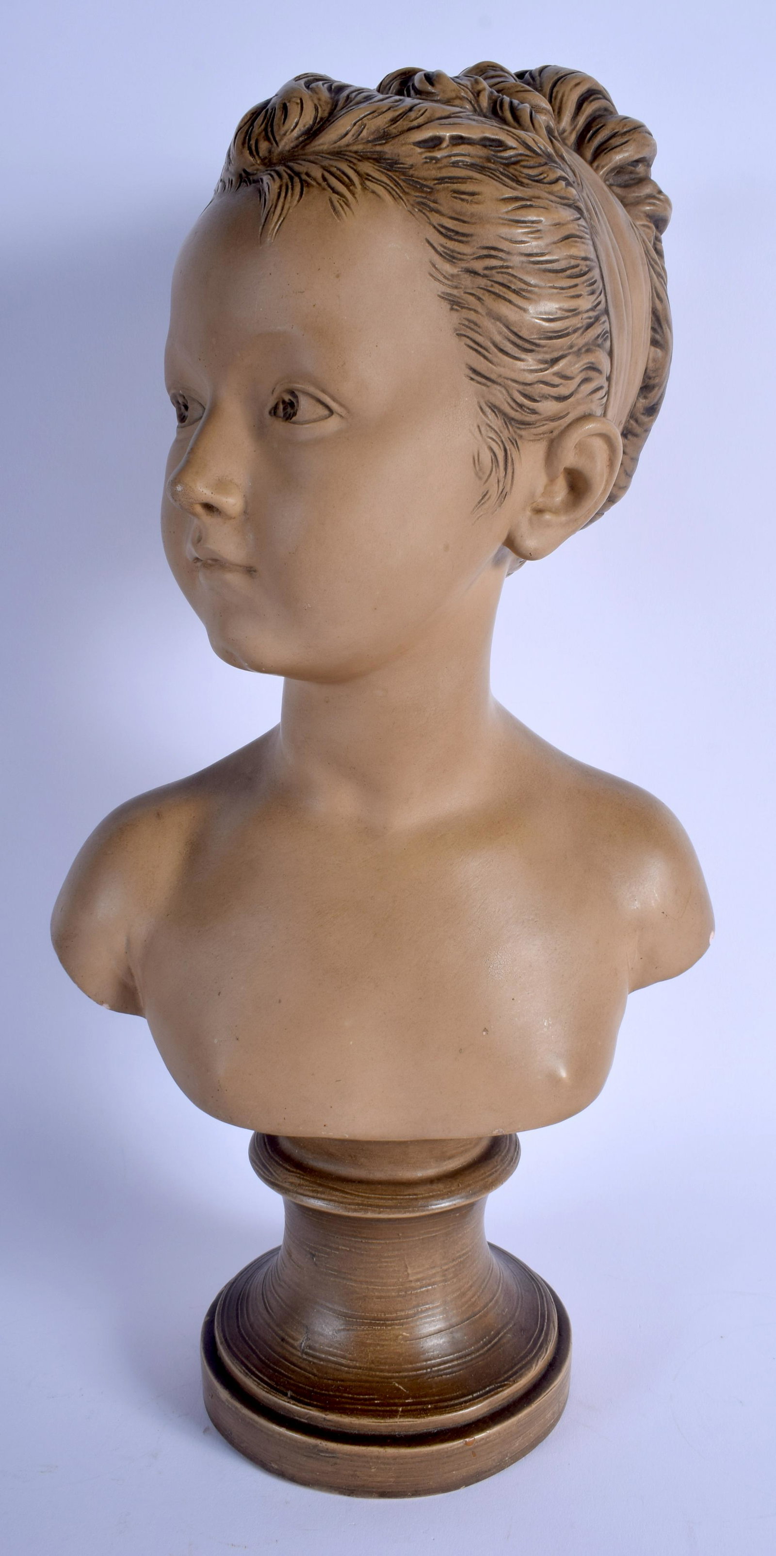AN ART DECO FRENCH TERRACOTTA BUST OF A GIRL modelled: AN ART DECO FRENCH TERRACOTTA BUST OF A GIRL modelled upon circular bases. 44 cm x 15 cm.