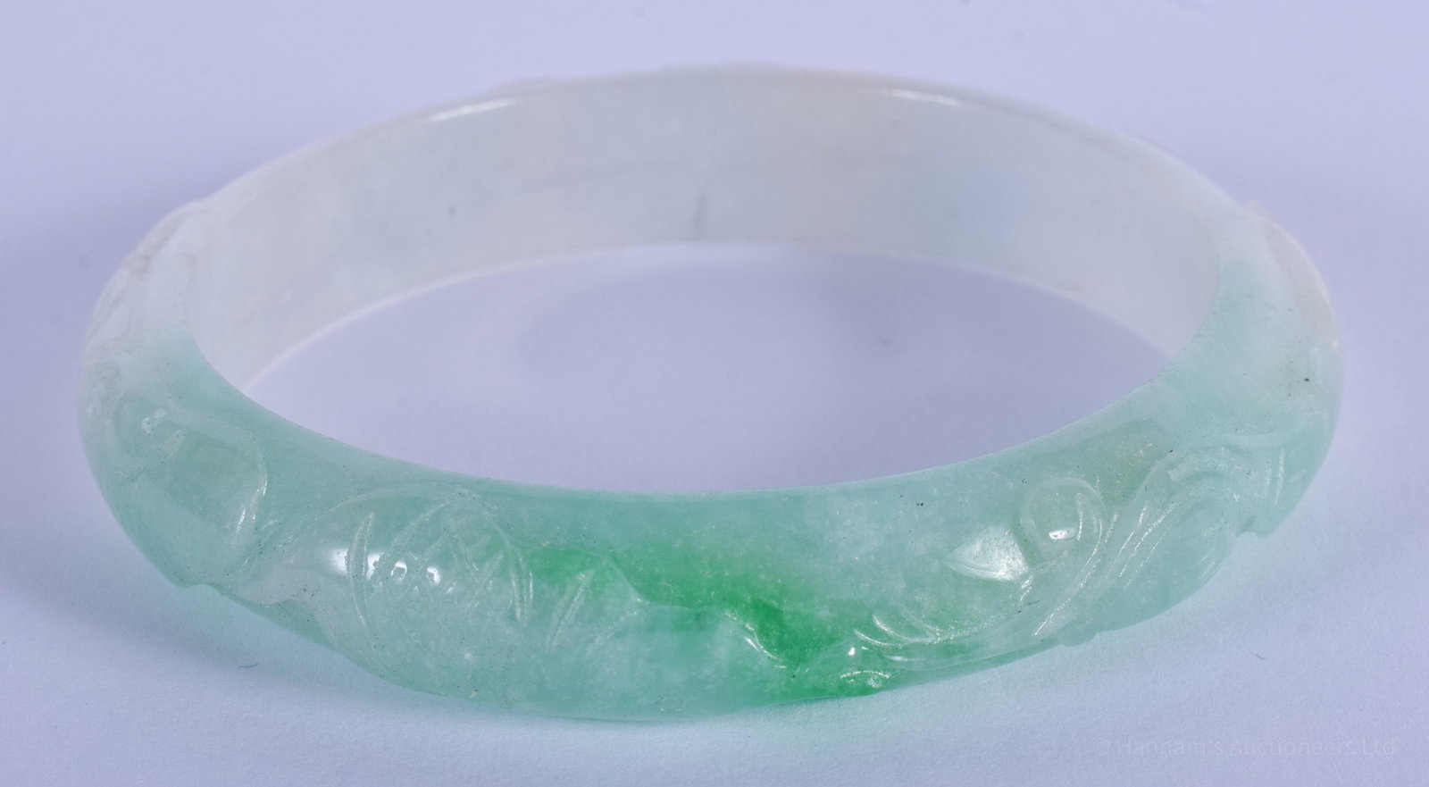 A CHINESE CARVED JADEITE BANGLE 20th Century. 7 cm: A CHINESE CARVED JADEITE BANGLE 20th Century. 7 cm diameter.