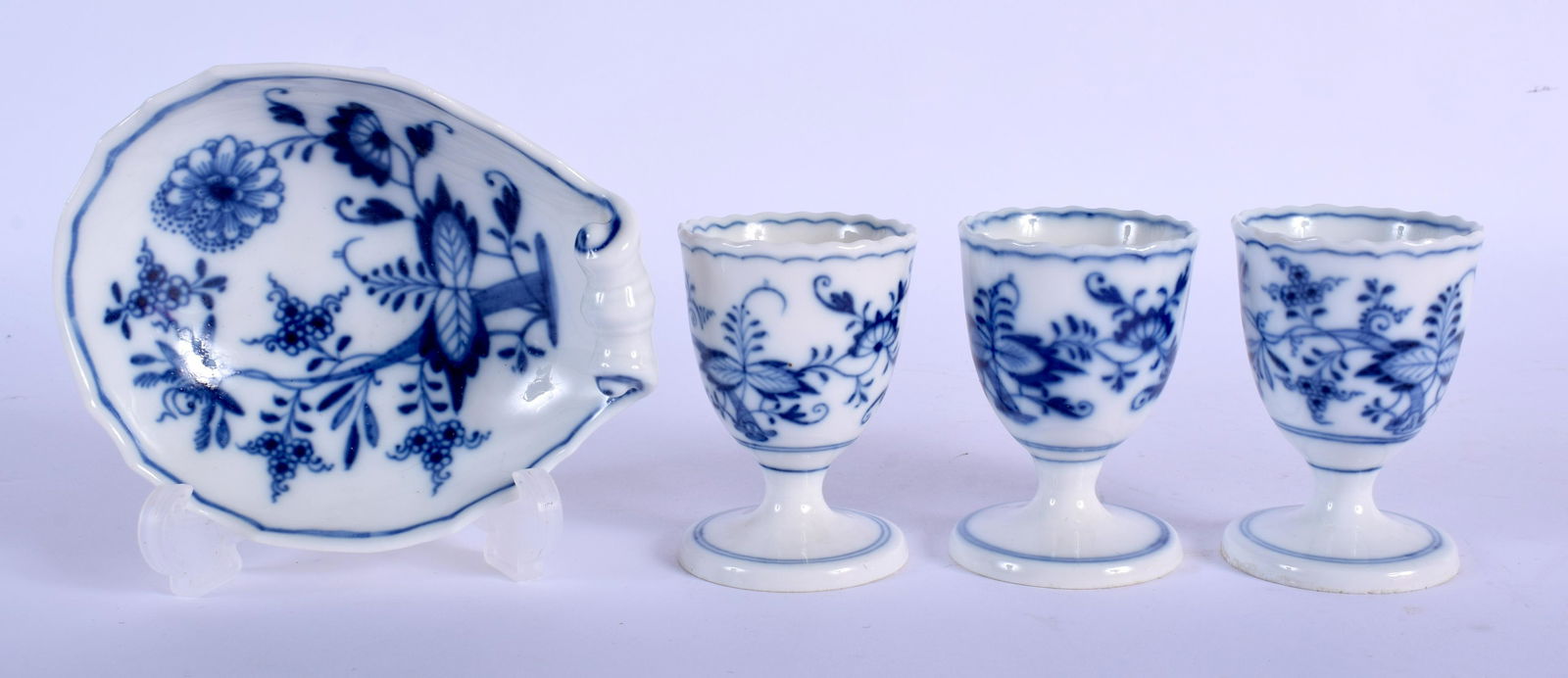 19th c. Meissen set of three egg cups in underglaze: 19th c. Meissen set of three egg cups in underglaze blue with the Onion pattern and a matching Meissen shell shaped dish, crossed swords mark in blue. Eggcups 7cm high