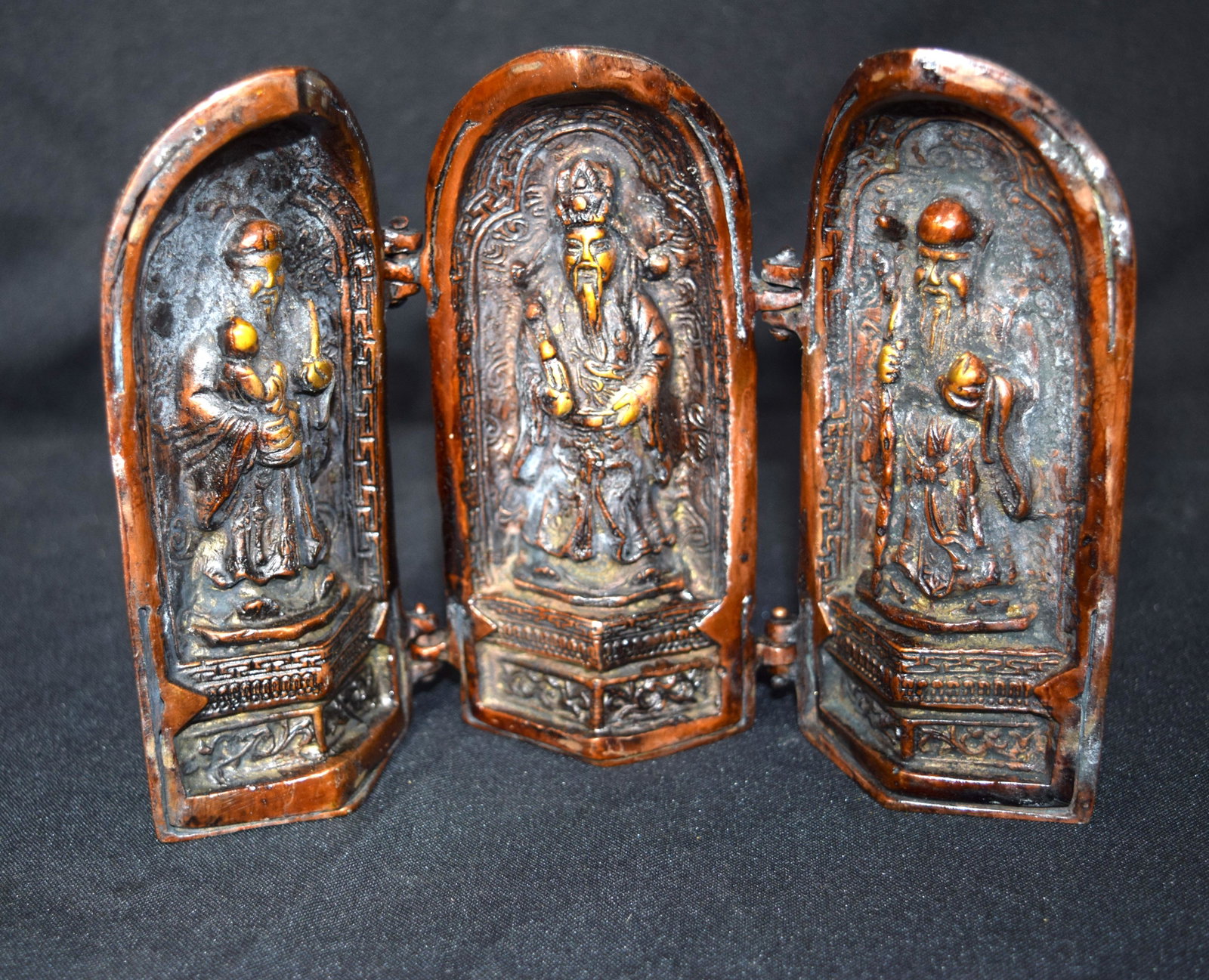 Bronze folding model of a Chinese temple opening to: Bronze folding model of a Chinese temple opening to display three priests. 15cm high