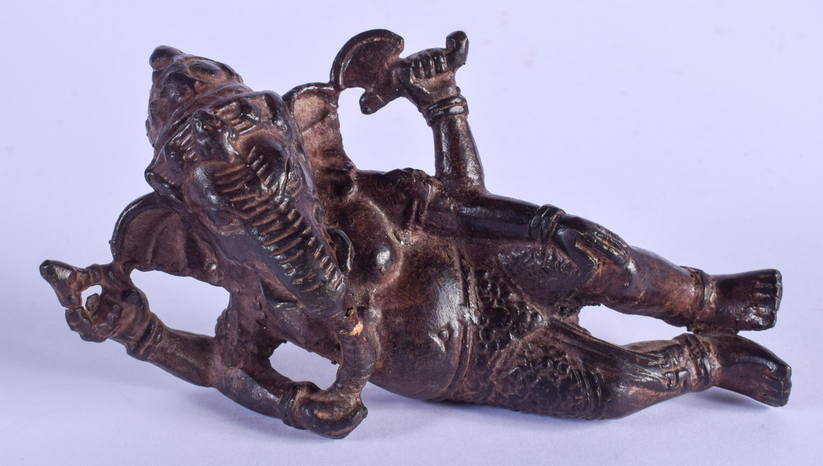 A 19TH CENTURY INDIAN BRONZE FIGURE OF A RECLINING: A 19TH CENTURY INDIAN BRONZE FIGURE OF A RECLINING GANESHA modelled in foliate robes. 15 cm x 10 cm.