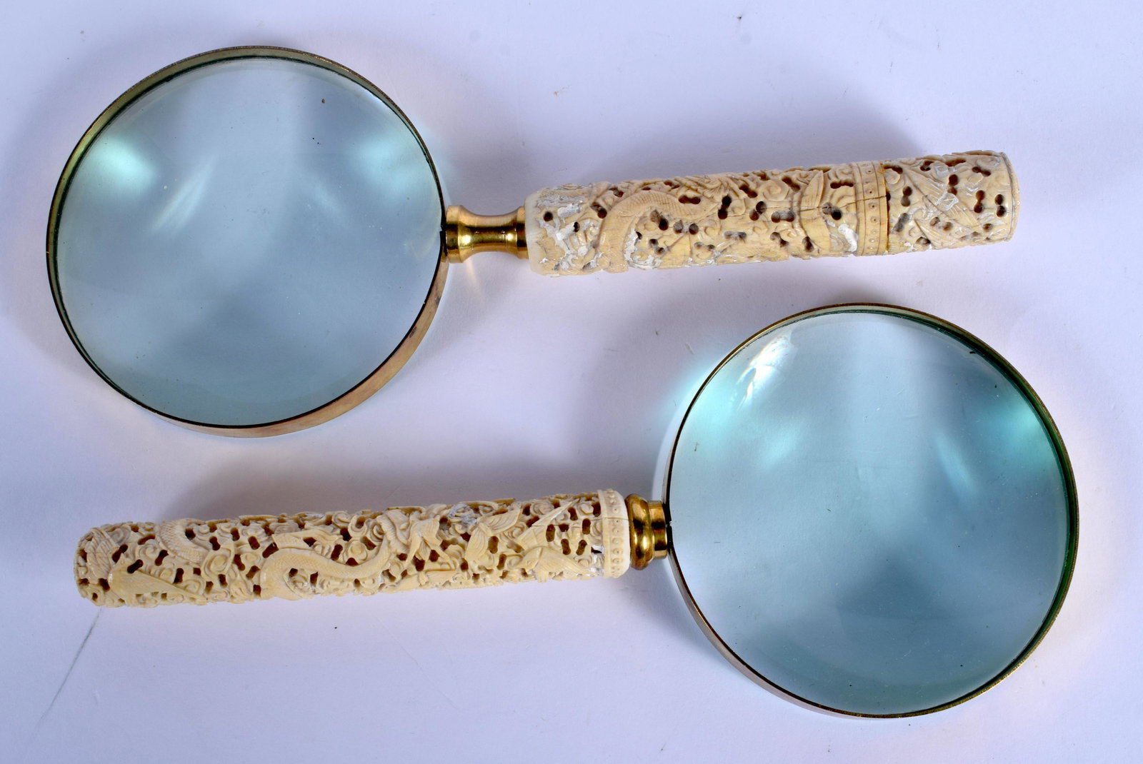 A PAIR OF 19TH CENTURY CHINESE CARVED CANTON BONE: A PAIR OF 19TH CENTURY CHINESE CARVED CANTON BONE MAGNIFYING GLASSES decorated with dragons and foliage. 24 cm x 10 cm.