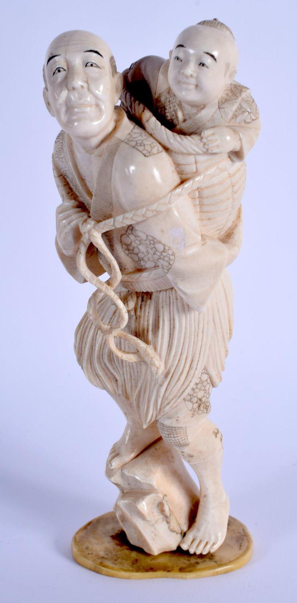 A 19TH CENTURY JAPANESE MEIJI PERIOD CARVED BONE: A 19TH CENTURY JAPANESE MEIJI PERIOD CARVED BONE OKIMONO modelled as a male and child. 19 cm x 5 cm.