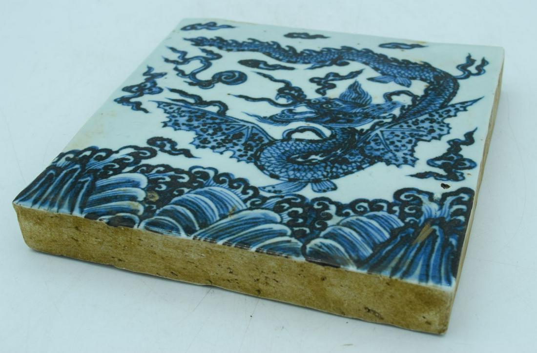 A Chinese blue and white temple tile decorated with a: A Chinese blue and white temple tile decorated with a dragon 20 x 20cm.