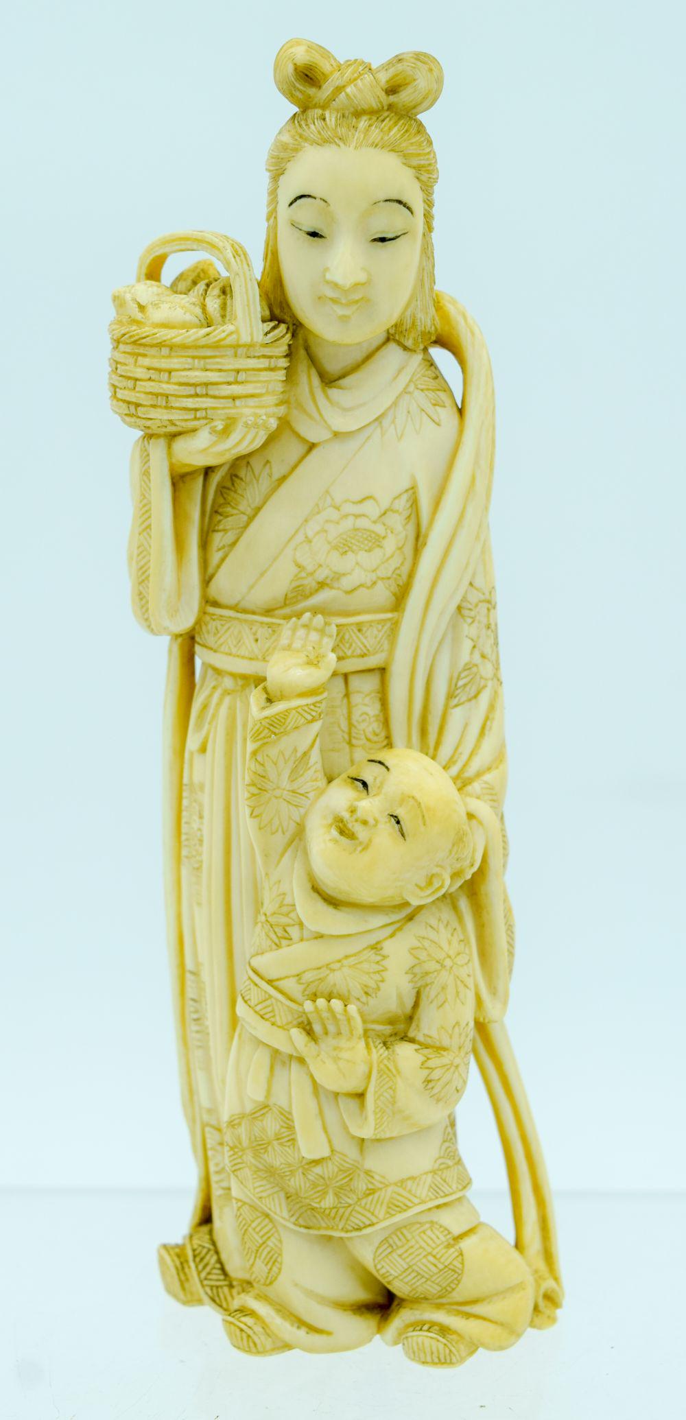 A 19TH CENTURY JAPANESE MEIJI PERIOD CARVED BONE: A 19TH CENTURY JAPANESE MEIJI PERIOD CARVED BONE OKIMONO modelled as a sanding female with boy. 18 cm high.