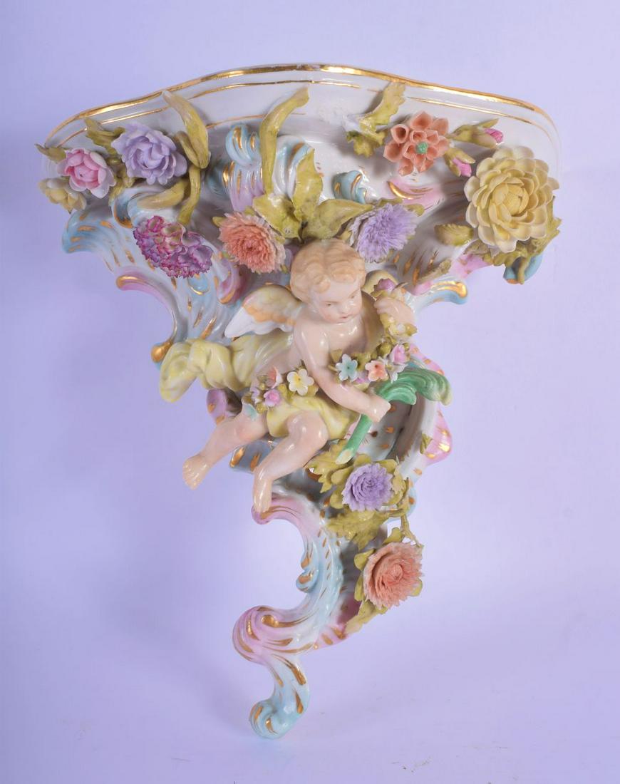 AN EARLY 20TH CENTURY GERMAN PORCELAIN ENCRUSTED WALL: AN EARLY 20TH CENTURY GERMAN PORCELAIN ENCRUSTED WALL BRACKET formed as a cherub amongst vines. 22 cm x 15 cm.