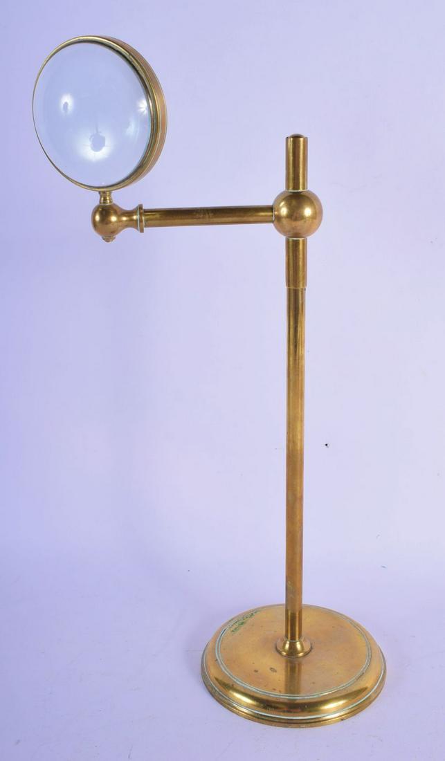 A STYLISH EARLY 20TH CENTURY BRASS MAGNIFYING LENS upon: A STYLISH EARLY 20TH CENTURY BRASS MAGNIFYING LENS upon a sliding body. 36 cm high.