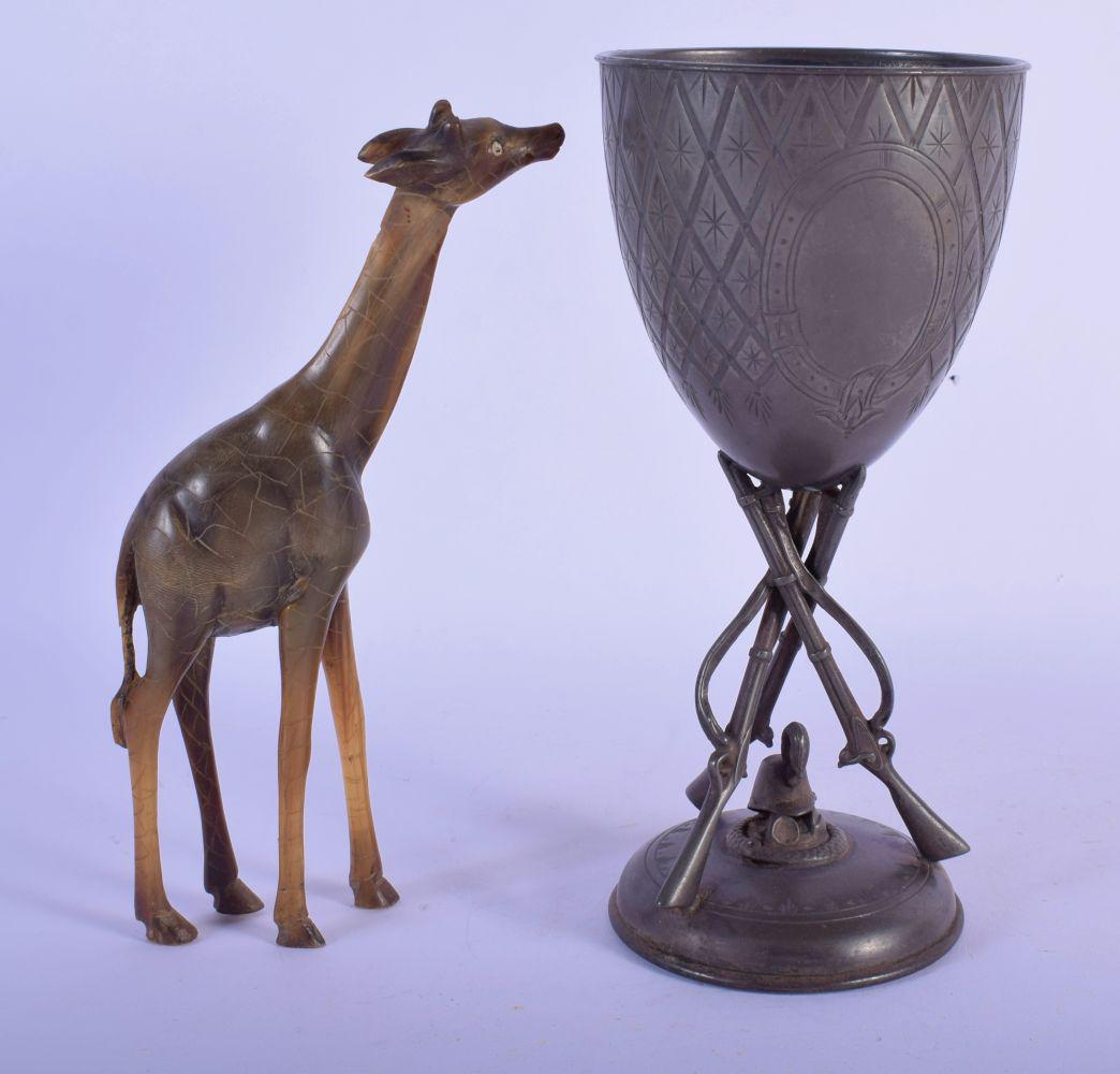 AN EARLY 20TH CENTURY MIDDLE EASTERN CARVED RHINOCEROS: AN EARLY 20TH CENTURY MIDDLE EASTERN CARVED RHINOCEROS HORN FIGURE OF A GIRAFFE together with a silver plated gun trophy. 22 cm high. (2)
