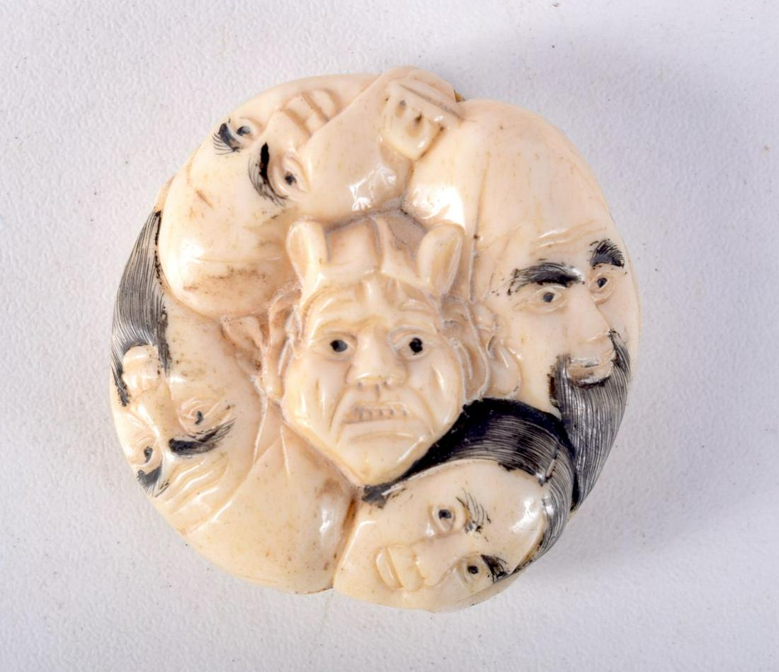 A JAPANESE BONE NETSUKE CARVED WITH FACES. 3.6cm x 1.6cm, weight 23.7g: A JAPANESE BONE NETSUKE CARVED WITH FACES. 3.6cm x 1.6cm, weight 23.7g