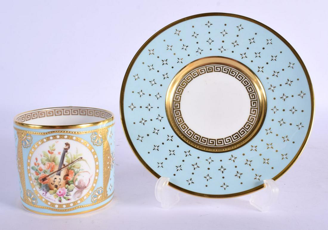 Lynton porcelain coffee can and stand, painted by Stefan Nowacki, signed & monogrammed, with a violi: Lynton porcelain coffee can and stand, painted by Stefan Nowacki, signed & monogrammed, with a violin and bow the light blue ground picked out with gilt and jewelled stars, and further tooled and gilt