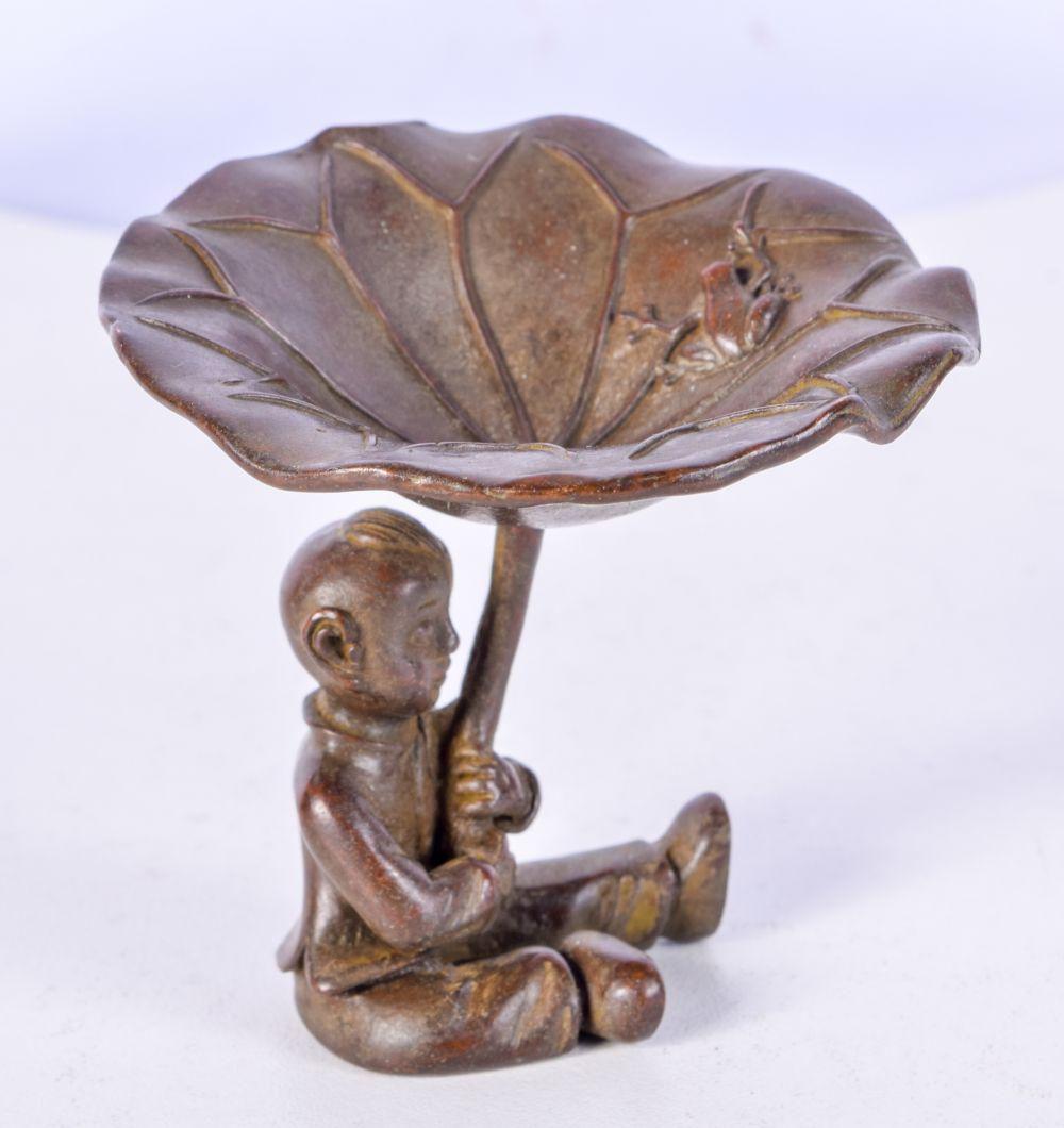 A JAPANESE BRONZ OF A SEATED BOY HOLDING ALOFT A LILLY PAD. 6.1cm x 6.3cm, weight 126.7g: A JAPANESE BRONZ OF A SEATED BOY HOLDING ALOFT A LILLY PAD. 6.1cm x 6.3cm, weight 126.7g