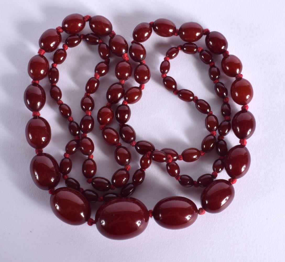 A GRADUATED CHERRY AMBER COLOURED BEAD NECKLACE.  Length 96cm, weight 66g (1 of 2)