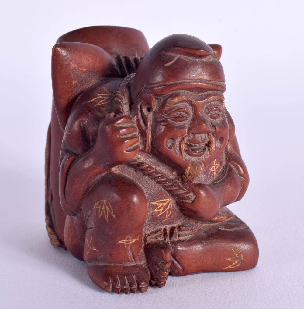 A JAPANESE CARVED WOOD PEN HOLDER IN THE FORM OF A SEATED MALE WITH A CARP ON HIS BACK. 5.8cm x 4.3: A JAPANESE CARVED WOOD PEN HOLDER IN THE FORM OF A SEATED MALE WITH A CARP ON HIS BACK. 5.8cm x 4.3cm x 6.3cm