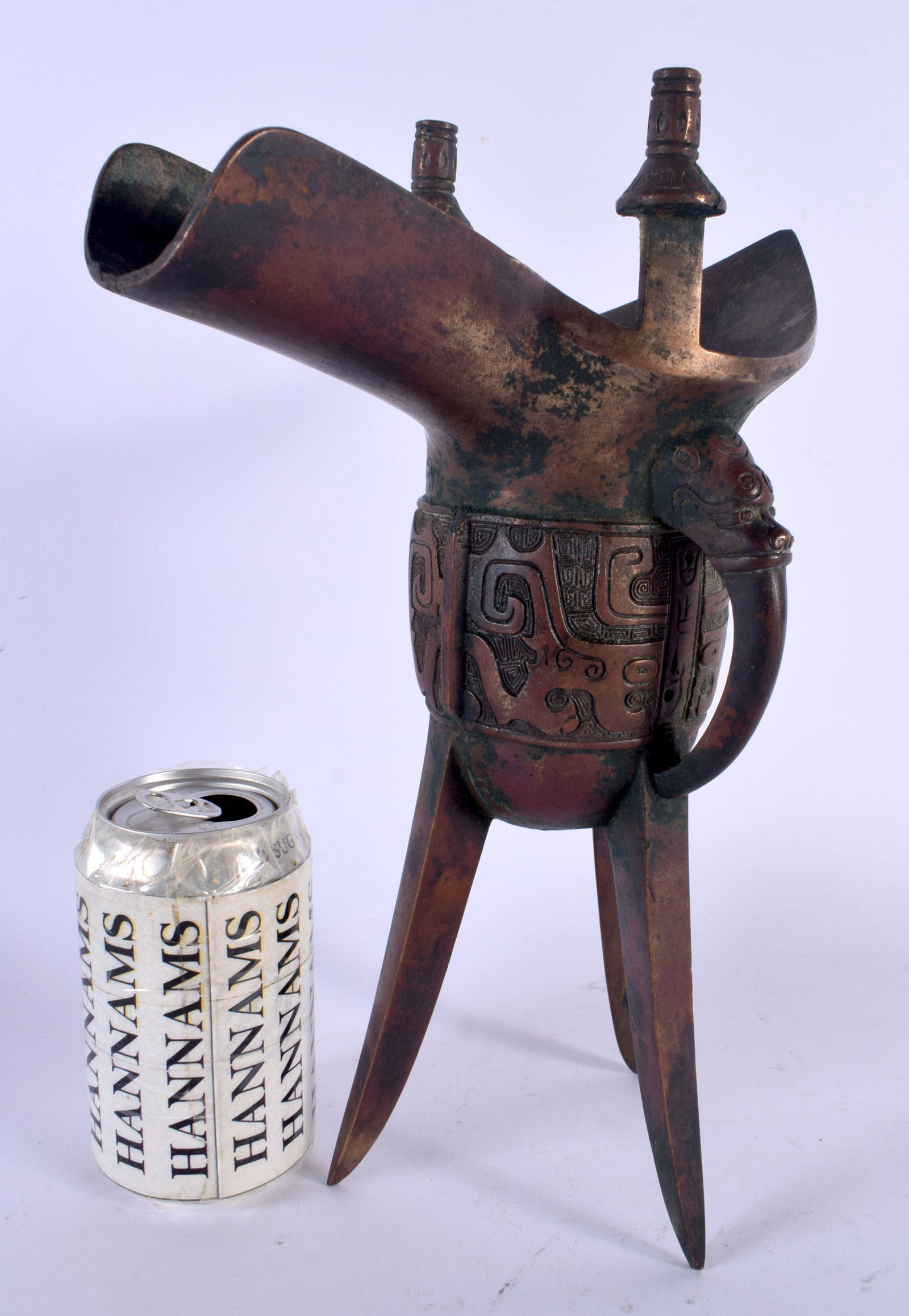 A RARE LARGE CHINESE QING DYNASTY BRONZE JUE CHIA WINE ARCHAIC WINE VESSEL Shang Style (C1766 to 112: A RARE LARGE CHINESE QING DYNASTY BRONZE JUE CHIA WINE ARCHAIC WINE VESSEL Shang Style (C1766 to 1122 BC) decorated with mask heads and archaic motifs. 30 cm x 15 cm.