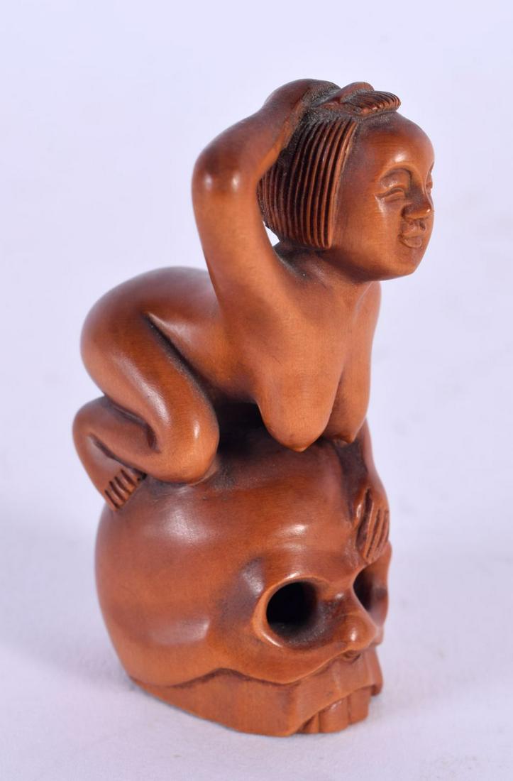 A JAPANESE CARVED BOXWOOD EROTIC NETSUKE modelled as a female upon a skull. 6 cm x 3 cm.: A JAPANESE CARVED BOXWOOD EROTIC NETSUKE modelled as a female upon a skull. 6 cm x 3 cm.
