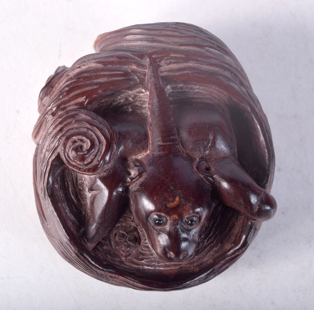 A CARVED WOOD NETSUKE MODELLED AS A CREATURE IN A BASKET. 5.4cm x 3.1cm: A CARVED WOOD NETSUKE MODELLED AS A CREATURE IN A BASKET. 5.4cm x 3.1cm