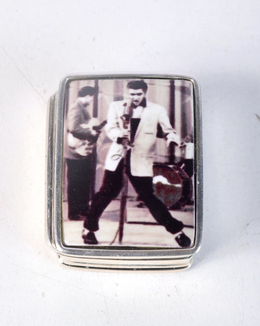 A SILVER PILL BOX WITH AN ENAMEL LID DECORATED AS ELVIS PRESLEY. Stamped Sterling, 2.5cm x 1.3cm x: A SILVER PILL BOX WITH AN ENAMEL LID DECORATED AS ELVIS PRESLEY. Stamped Sterling, 2.5cm x 1.3cm x 3.1cm, weight 19.4g