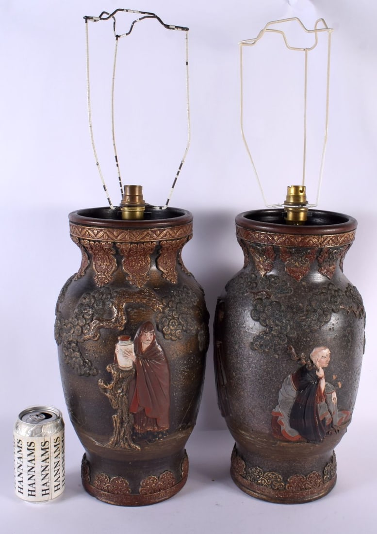 A LARGE PAIR OF 19TH JAPANESE POTTERY COUNTRY HOUSE LAMPS depicting figures in relief with dragons.: A LARGE PAIR OF 19TH JAPANESE POTTERY COUNTRY HOUSE LAMPS depicting figures in relief with dragons. 57 cm high.