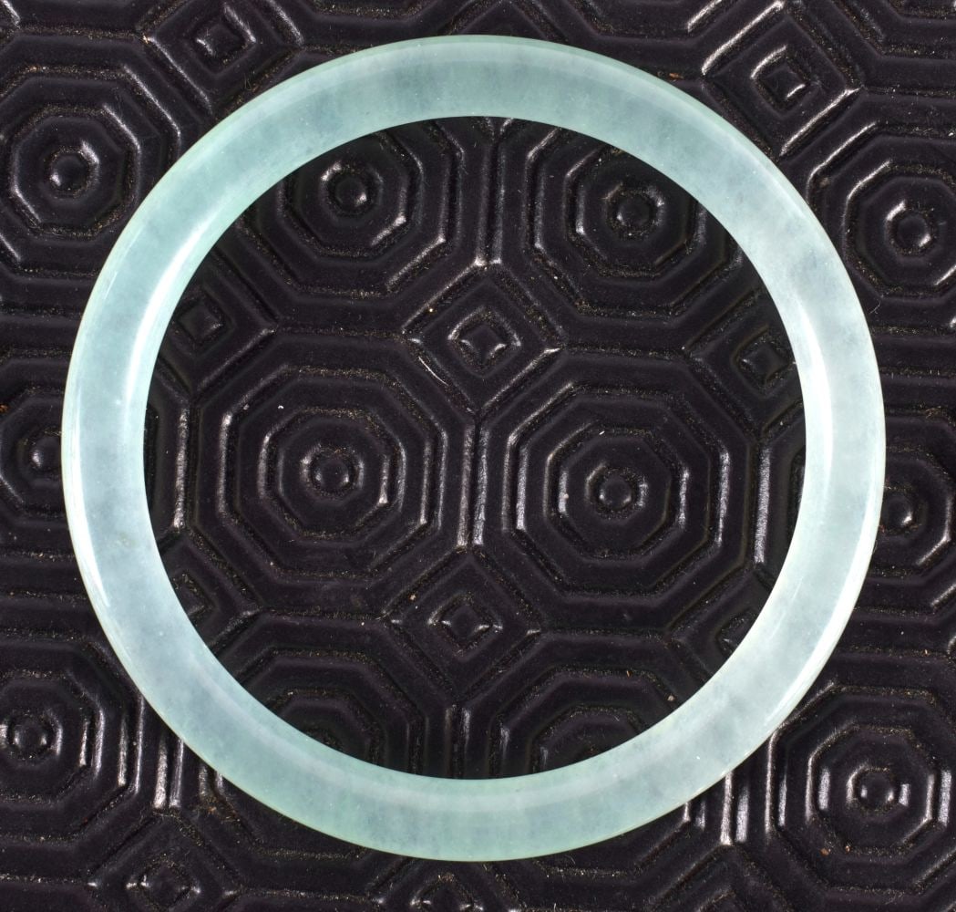 A CHINESE CARVED JADE BANGLE 20th Century. 28.4 grams. 6.5 cm diameter.: A CHINESE CARVED JADE BANGLE 20th Century. 28.4 grams. 6.5 cm diameter.