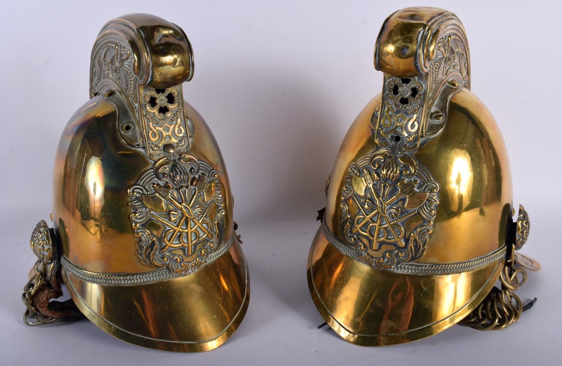 A PAIR OF VICTORIAN BRASS FIREMAN'S HELMETS. 27 cm x 18 cm. (1 of 4)
