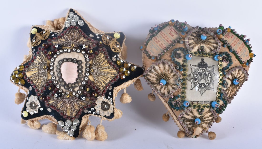 A PAIR OF ANTIQUE EMBROIDERED SILK AND BEAD WORK SWEETHEART PIN CUSHIONS one for the Devonshire Regi: A PAIR OF ANTIQUE EMBROIDERED SILK AND BEAD WORK SWEETHEART PIN CUSHIONS one for the Devonshire Regiment. Largest 19 cm x 15 cm. (2)