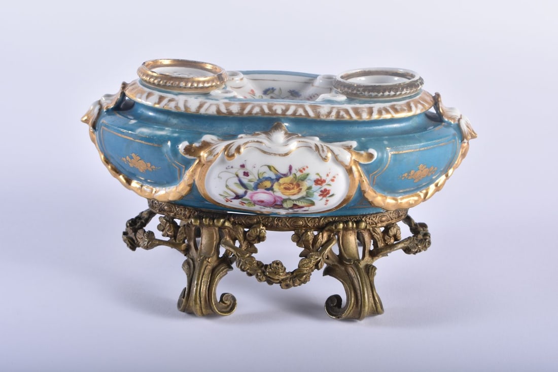 A 19TH CENTURY FRENCH PARIS SEVRES TYPE PORCELAIN INKWELL upon a gilt bronze scrolling base. 23 cm x: A 19TH CENTURY FRENCH PARIS SEVRES TYPE PORCELAIN INKWELL upon a gilt bronze scrolling base. 23 cm x 13 cm.